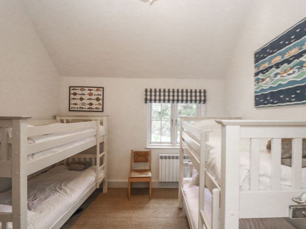 A bedroom with bunk beds and a chair at Wood Meadow in Helston
