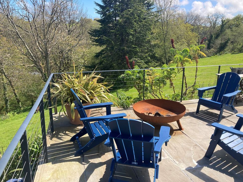 An outdoor patio with blue chairs and a fire pit at Wood Meadow in Helston