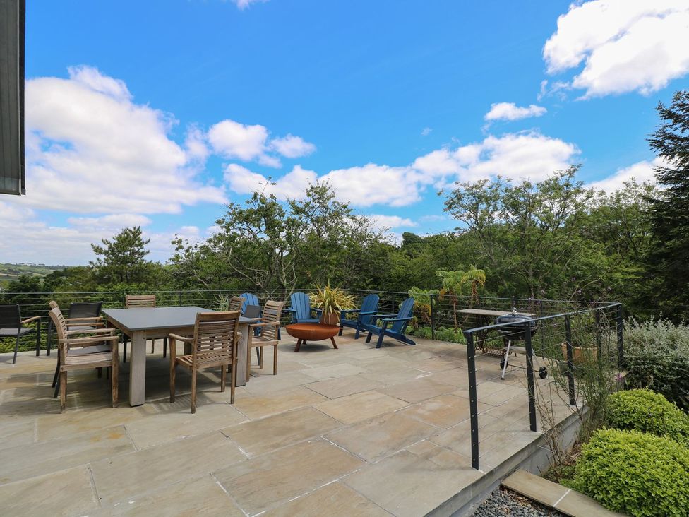 An outdoor patio with a table and chairs at Wood Meadow in Helston