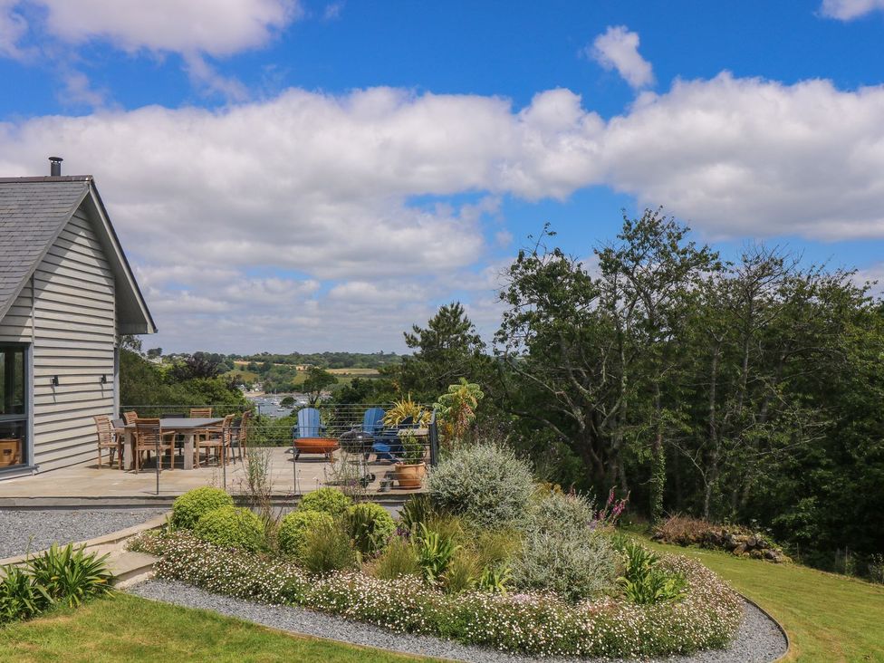 An outdoor patio with a dining table and chairs at Wood Meadow in Helston