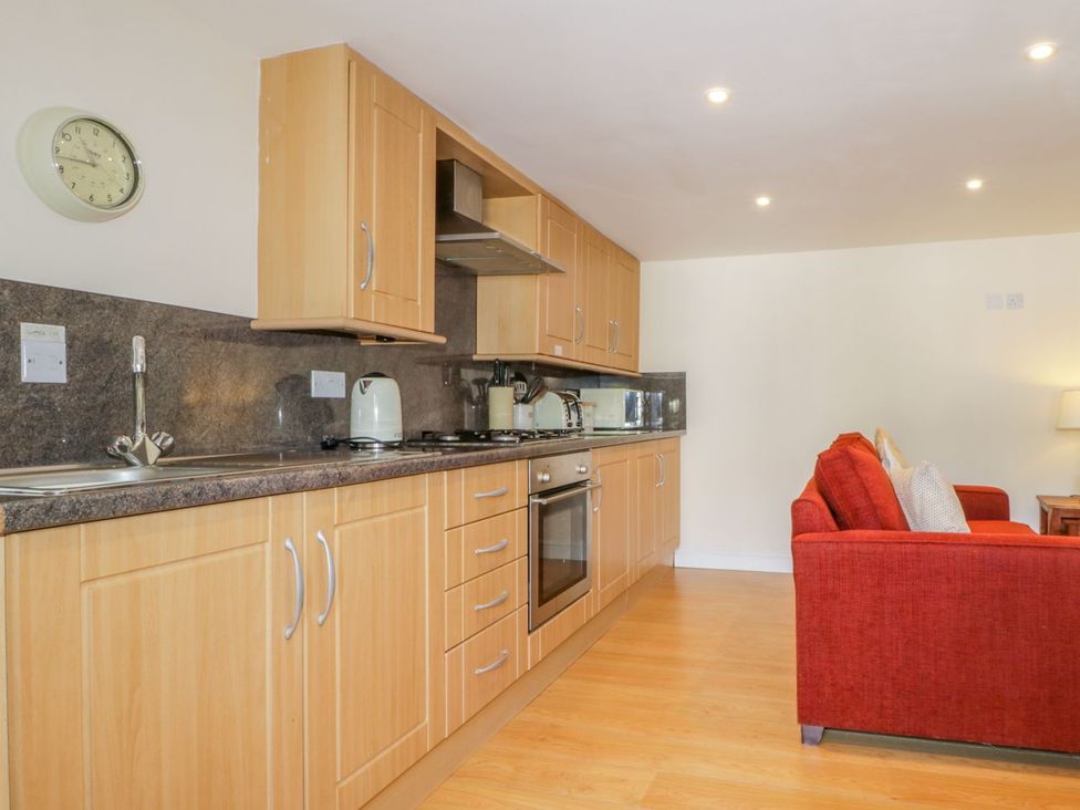 A kitchen with wooden cabinets and a red sofa at Farmhouse Cottage in Keswick