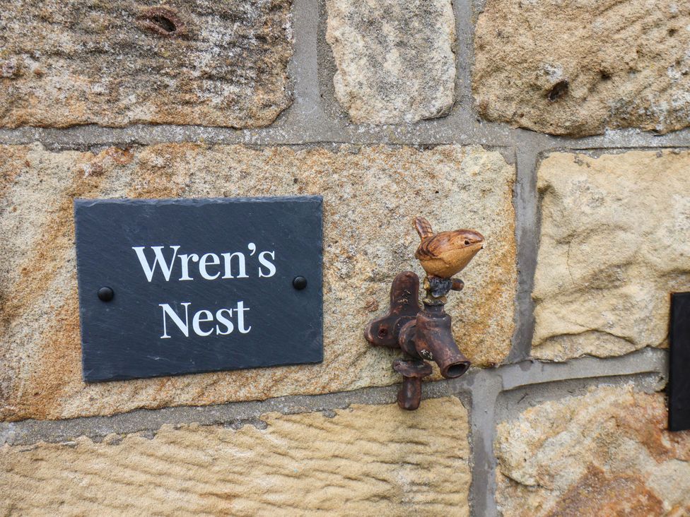 A plaque with Wren's Nest and a bird faucet at Wren's Nest in Lealholm
