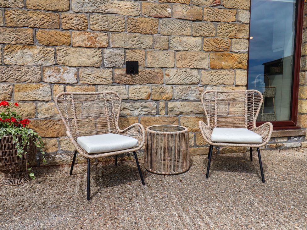 Two chairs and a table in front of a stone wall at Swallow Cottage Lealholm