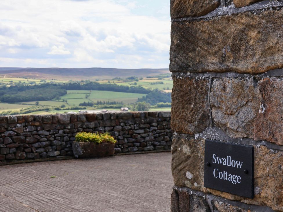 A stone wall with a sign for Swallow Cottage at Lealholm