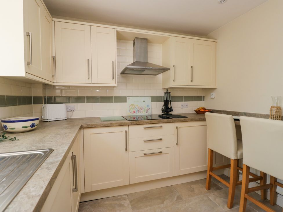 A kitchen with cabinets, countertop, stove, and bar stools at Bobbin Nook 