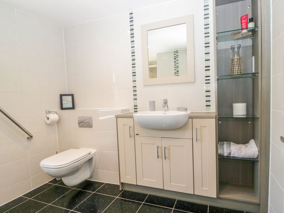 A bathroom with a sink, toilet, and storage cabinet at Bobbin Nook 