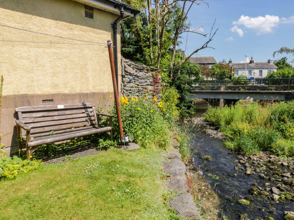 A garden area with a wooden bench and flowers beside a stream at Bobbin Nook
