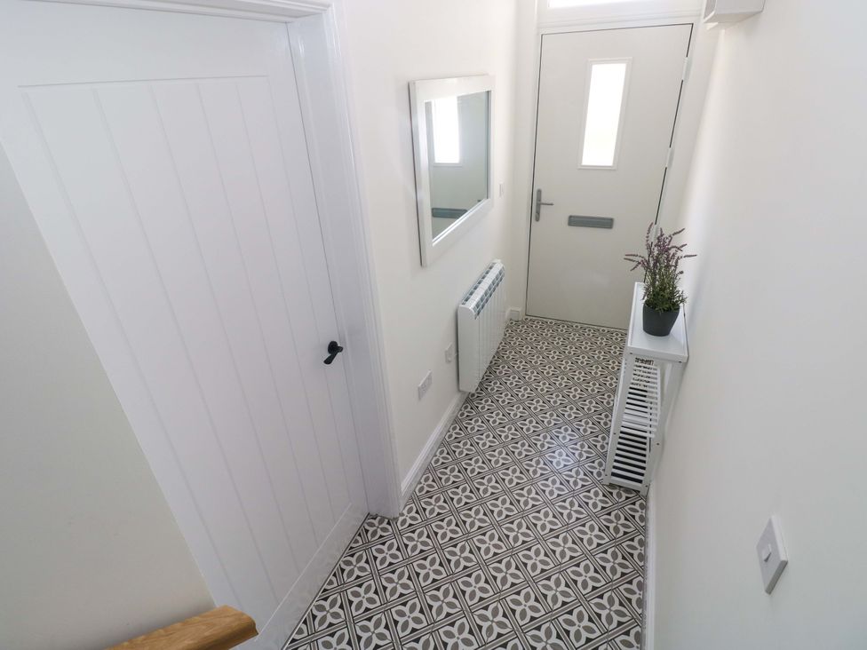 A hallway featuring a door, mirror, radiator, and plant at Mountain View Cottage in Ystradgynlais