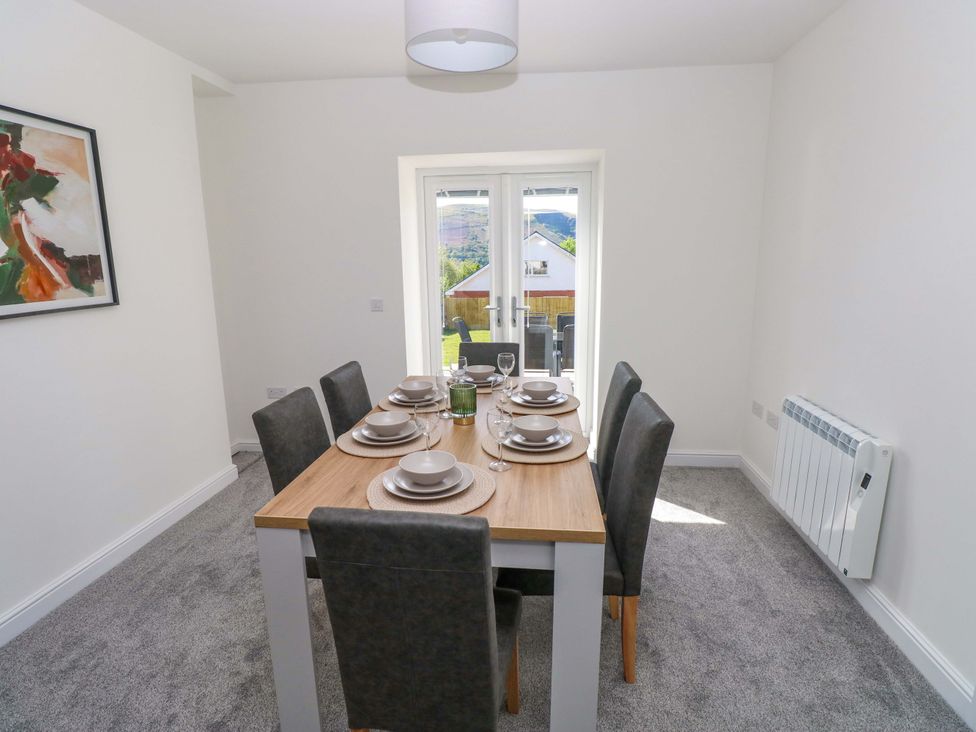 A dining room with a table set for six at Mountain View Cottage in Ystradgynlais
