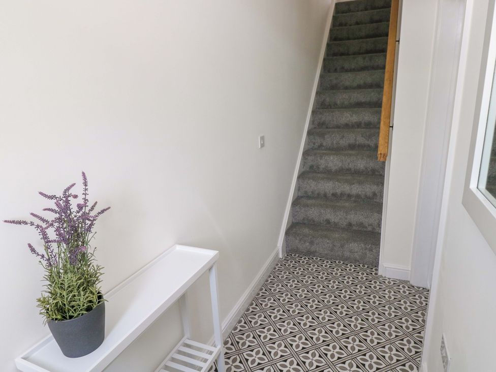 A hallway with a flower pot and staircase at Mountain View Cottage Ystradgynlais