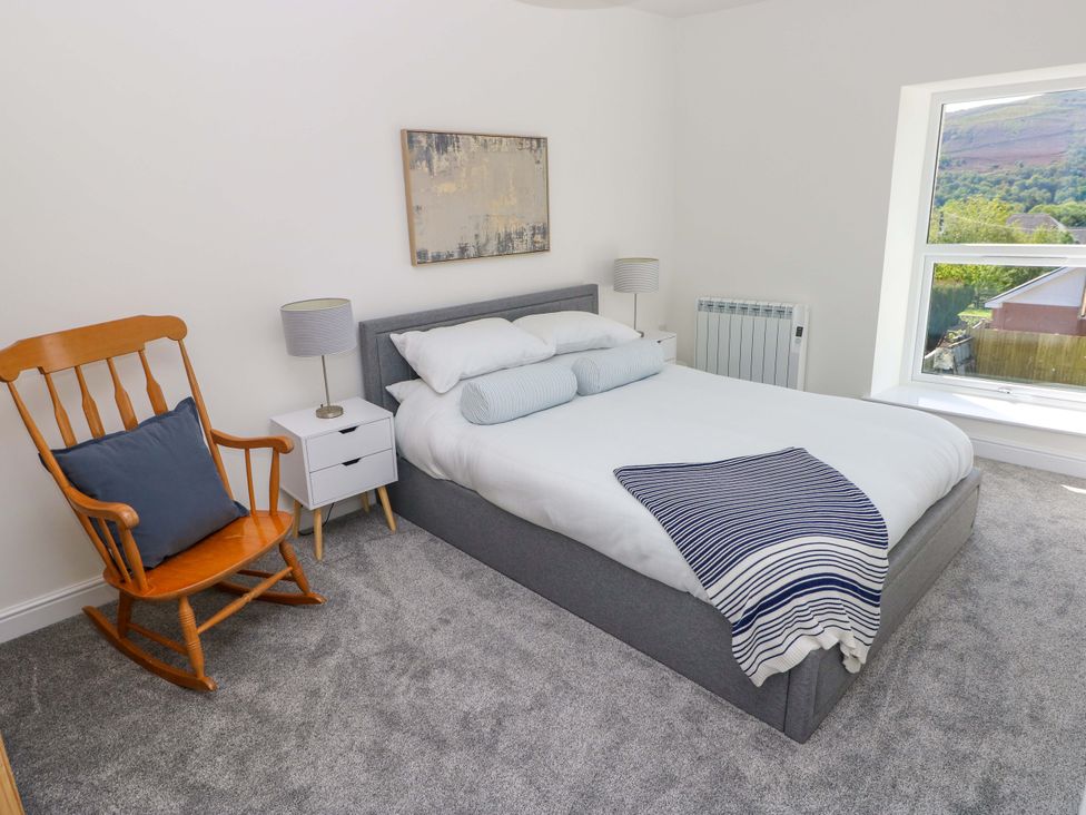 A bedroom with a bed and rocking chair at Mountain View Cottage in Ystradgynlais