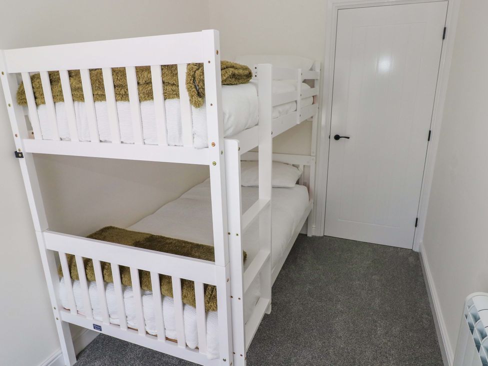 A bunk bed with sheets and blankets in a bedroom at Mountain View Cottage in Ystradgynlais