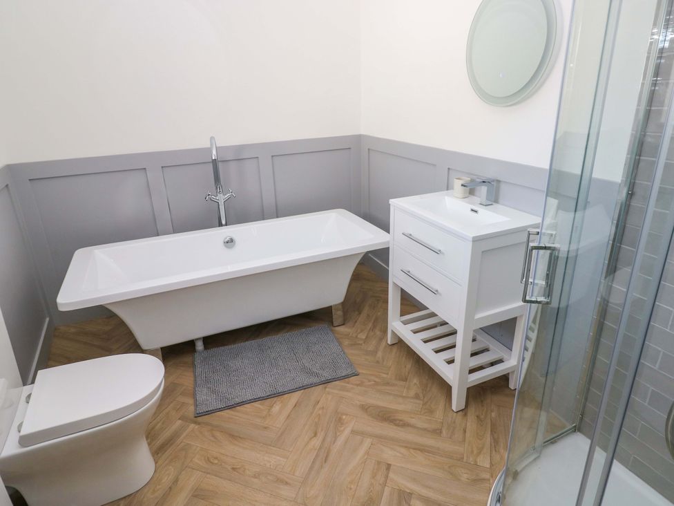 A bathroom with a bathtub, toilet, vanity, and shower at Mountain View Cottage in Ystradgynlais