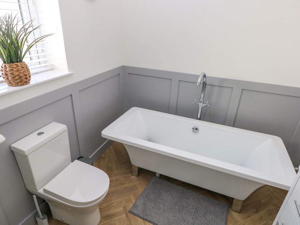 A bathroom with a toilet and bath tub at Mountain View Cottage Ystradgynlais