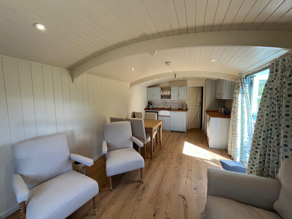 A living room with chairs and a kitchen area at The Orchard in Ringstead