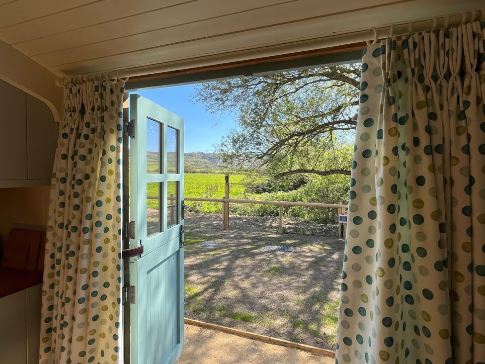 A door and curtains opening to a view of trees and a fenced field at The Orchard in Ringstead