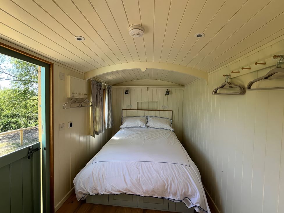 A bedroom with a bed and coat hangers at The Orchard in Ringstead