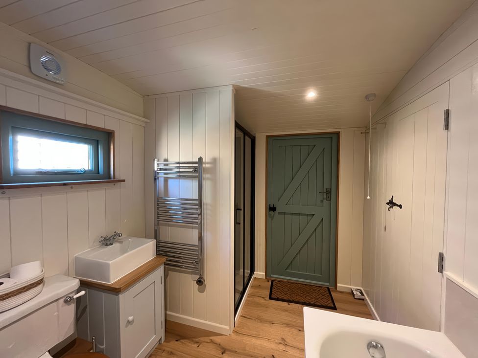 A bathroom with a toilet, sink, towel rail, and shower at The Orchard in Ringstead