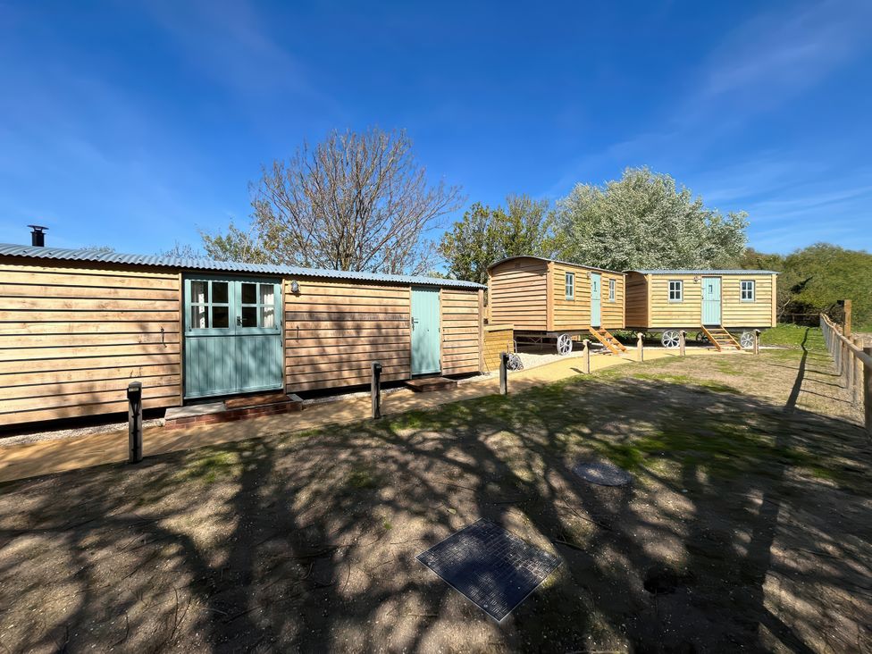 Outdoor area with wooden cabins and trees at The Orchard in Ringstead