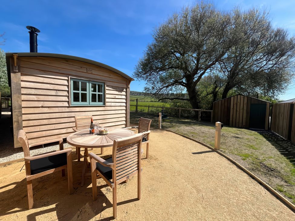 A wooden cabin with an outdoor table and chairs at The Orchard in Ringstead