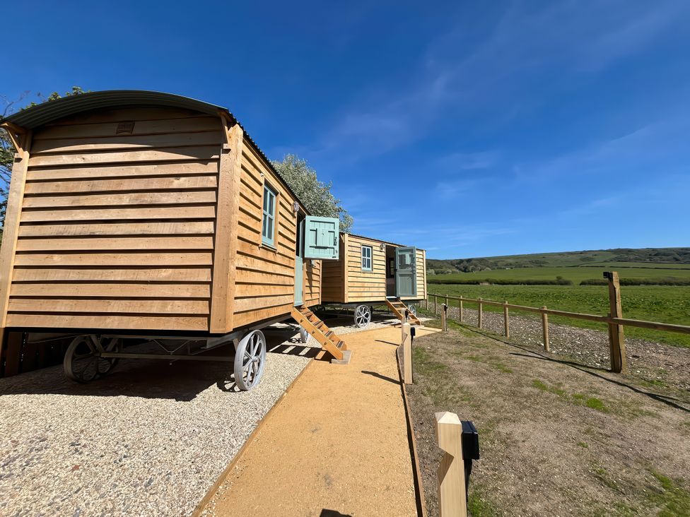 Two wooden tiny homes with wheels and a pathway at The Orchard in Ringstead
