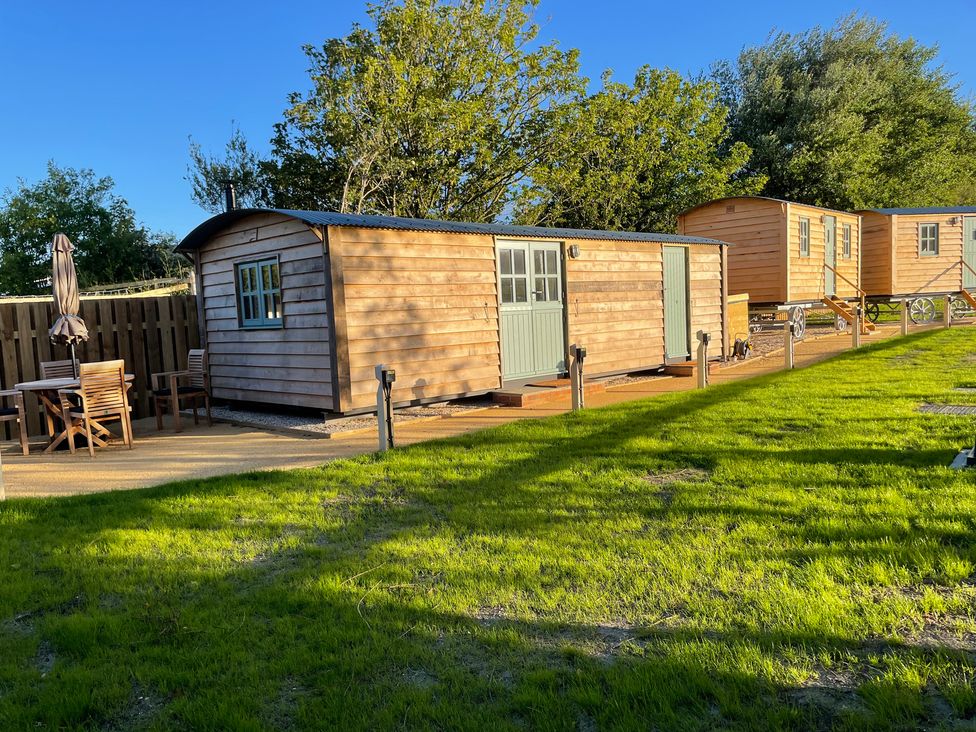 A wooden cabin with outdoor dining furniture at The Orchard in Ringstead