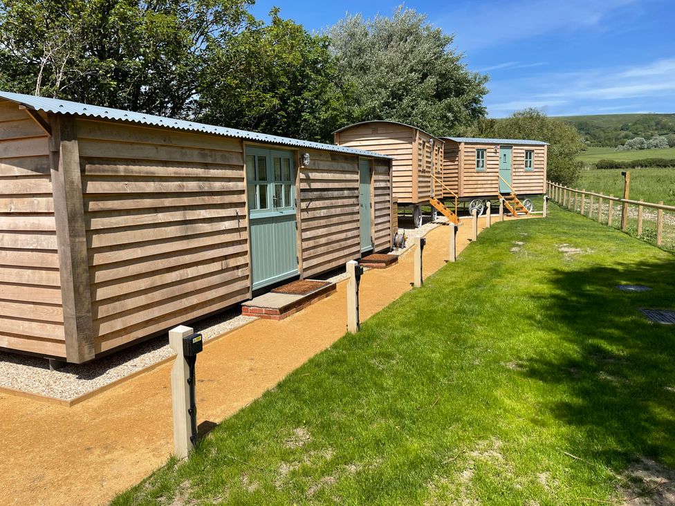 A row of cabins with doors and steps on a grassy area at The Orchard in Ringstead