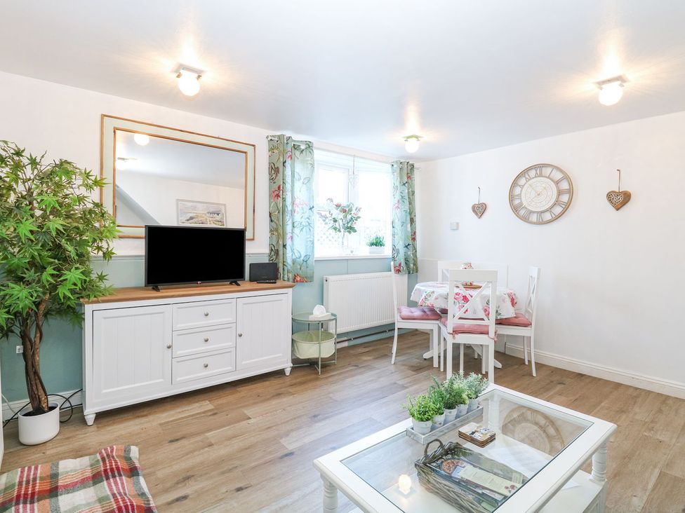 A living room with a television and table at Hideaway Cottage in Hunstanton