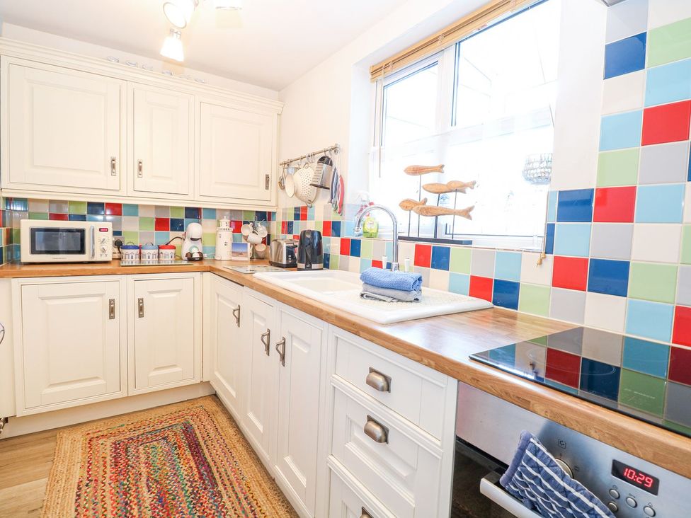 A kitchen with cabinets and appliances at Hideaway Cottage in Hunstanton