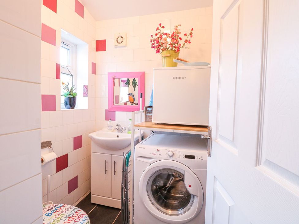 A bathroom with a washing machine and sink at Hideaway Cottage in Hunstanton
