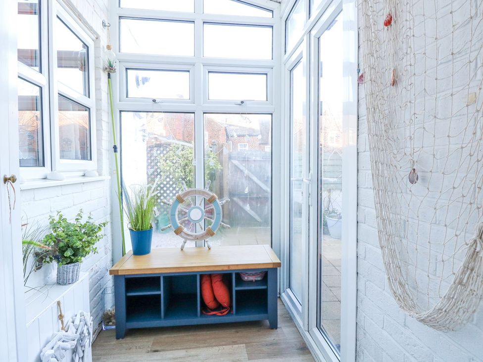 A conservatory with a table and plants at Hideaway Cottage in Hunstanton