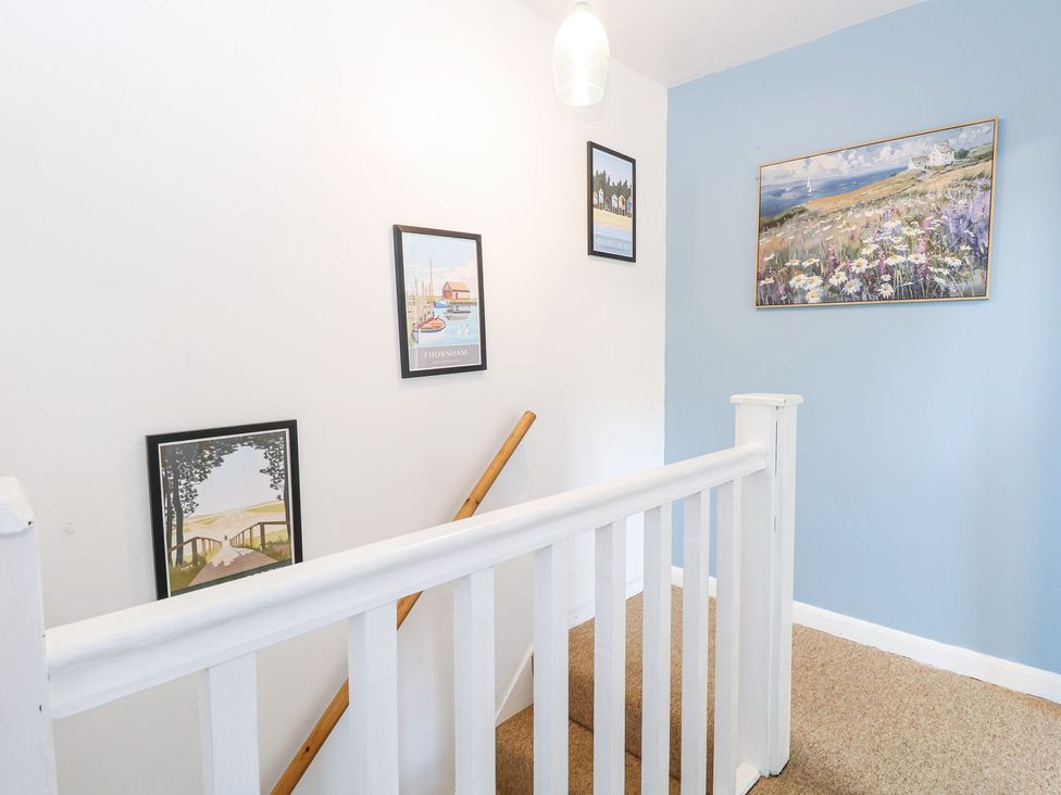A staircase with paintings on the wall at Hideaway Cottage in Hunstanton