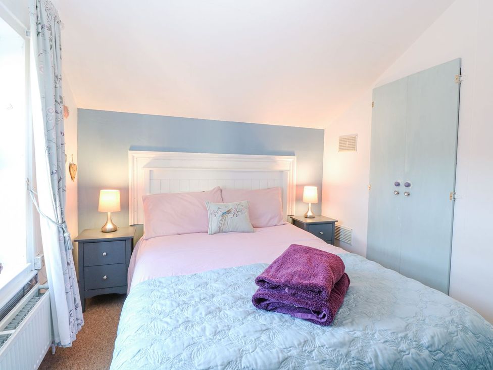 A bedroom with a bed and nightstands at Hideaway Cottage in Hunstanton