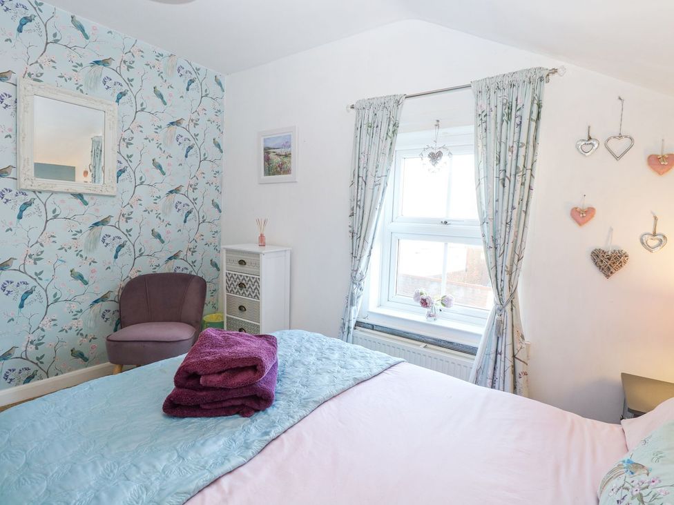 A bedroom with a bed and a mirror at Hideaway Cottage in Hunstanton