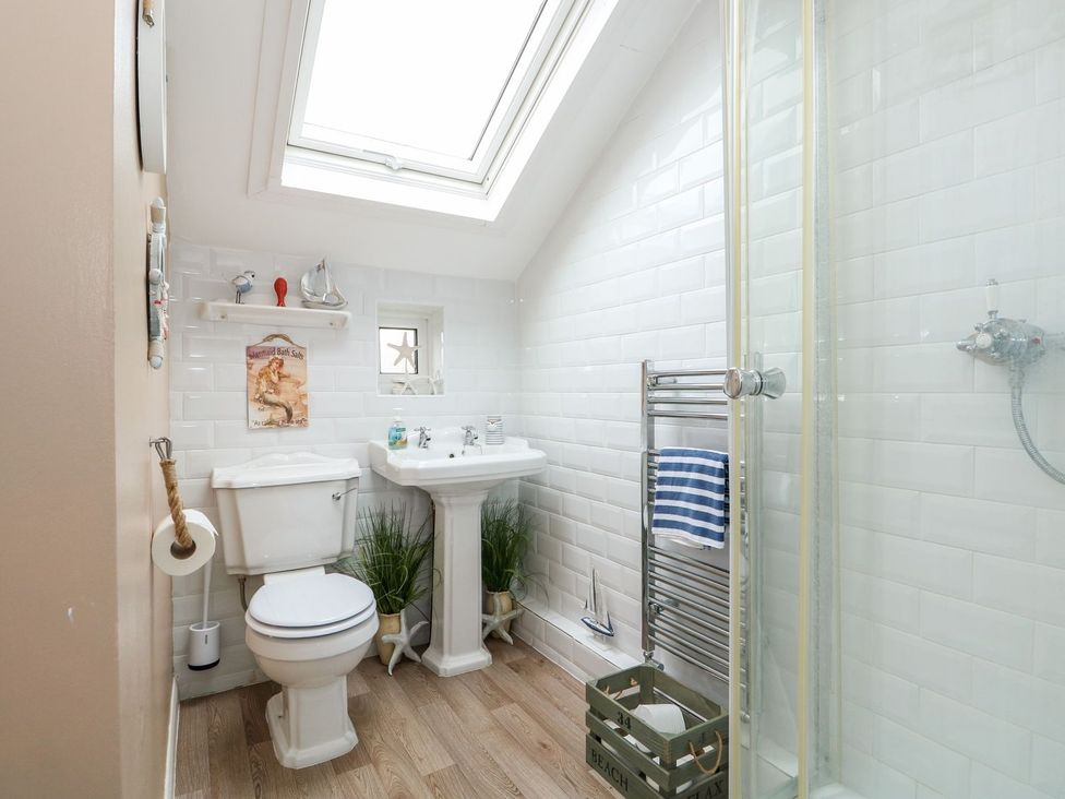A bathroom with a sink, toilet, and shower at Hideaway Cottage in Hunstanton