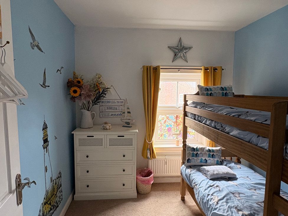 A bedroom with a bunk bed and flower vase at Hideaway Cottage in Hunstanton