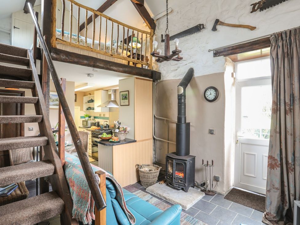 A living room with a sofa and wood stove at Ty Gwenno in Criccieth