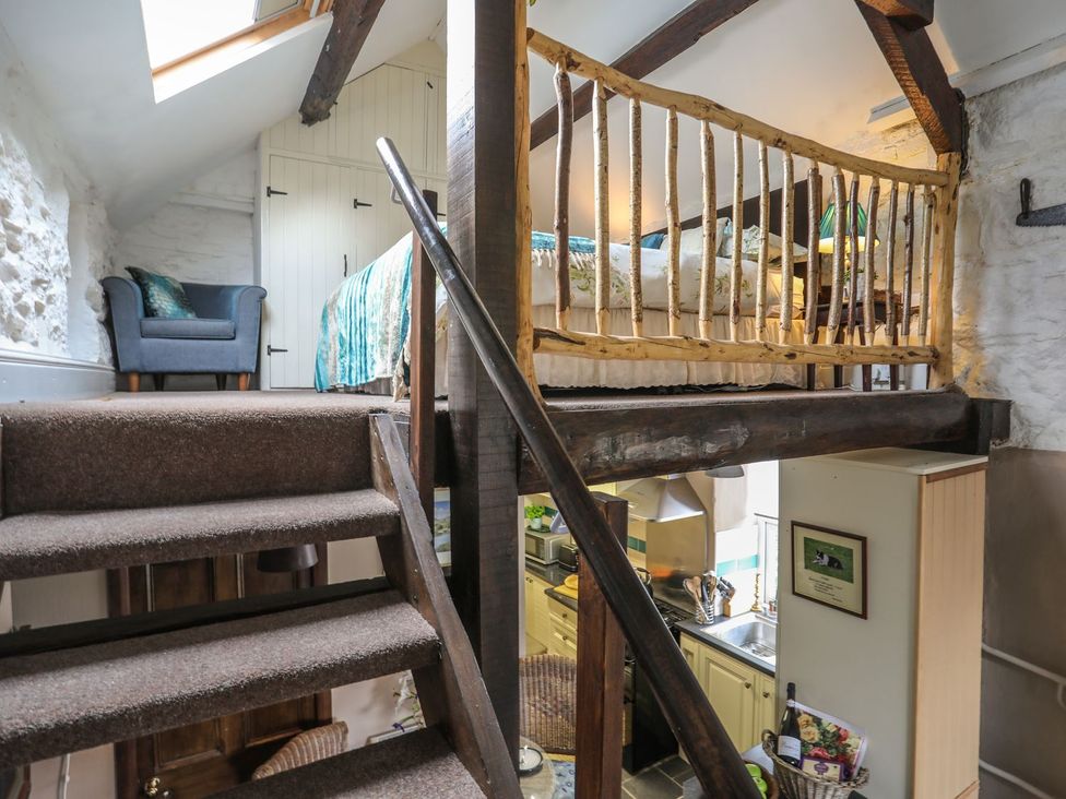 A living room with a staircase and a bed at Ty Gwenno Criccieth