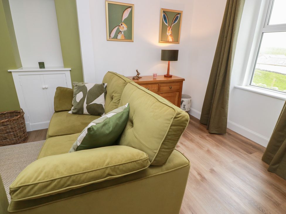 A living room with a green sofa and wooden table at South Kirklauchline Farm in Stoneykirk near Sandhead
