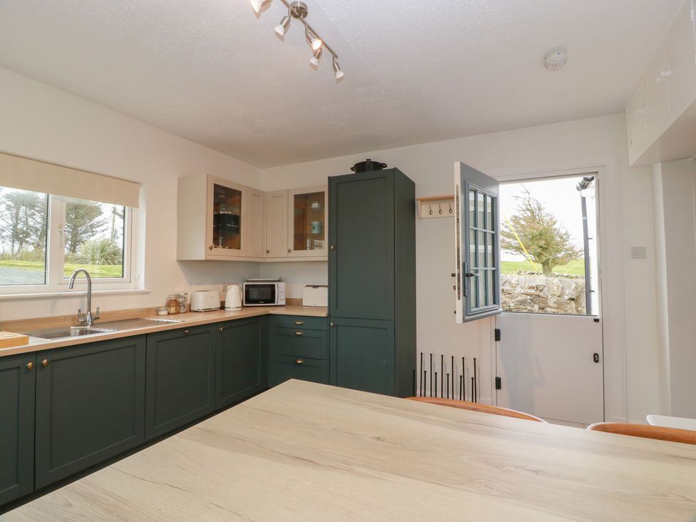 A kitchen featuring a countertop, sink, microwave, and door at South Kirklauchline Farm in Stoneykirk near Sandhead