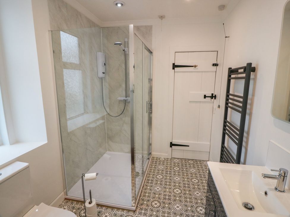 A bathroom with a shower, sink, toilet, and towel radiator at South Kirklauchline Farm Stoneykirk near Sandhead