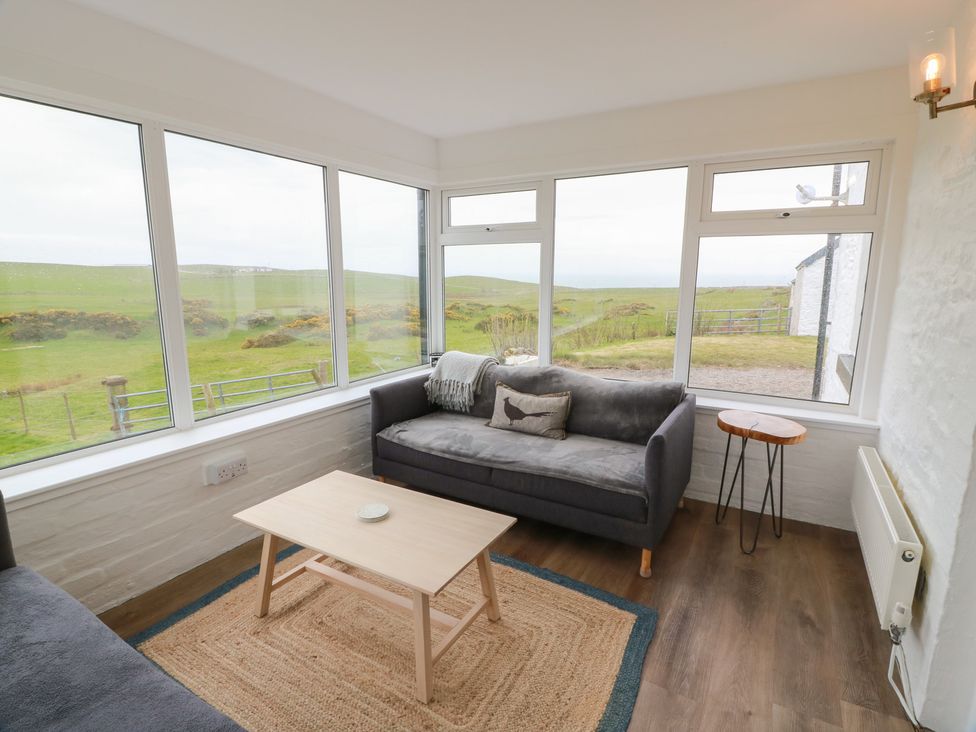 A sunroom with a sofa and table at South Kirklauchline Farm Stoneykirk near Sandhead