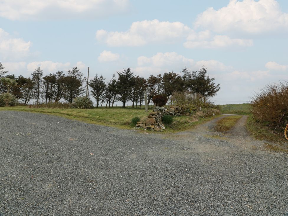 A gravel driveway with trees and a stone wall at South Kirklauchline Farm in Stoneykirk near Sandhead