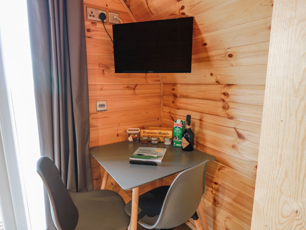 A table with chairs and a television in a cabin at Keith in Stoneykirk near Sandhead