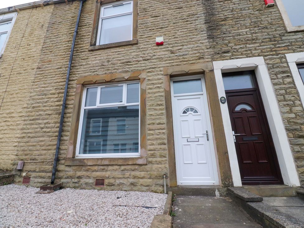 A white and brown door with a window on a stone wall at 46 Marlborough Road in Accrington