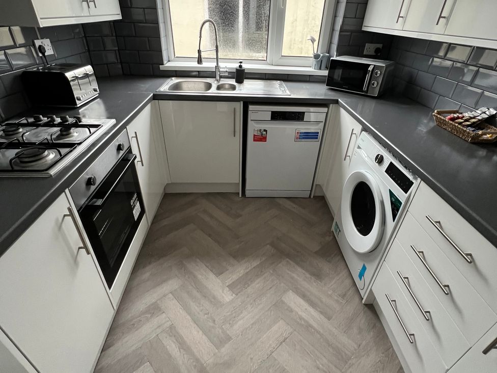 A kitchen with appliances including a sink, stove, and washing machine at 46 Marlborough Road Accrington