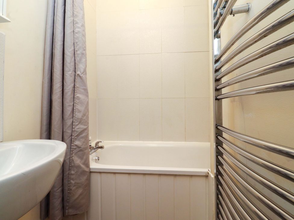 A bathroom with a bathtub, sink, and towel rail at Victoria Place in Accrington