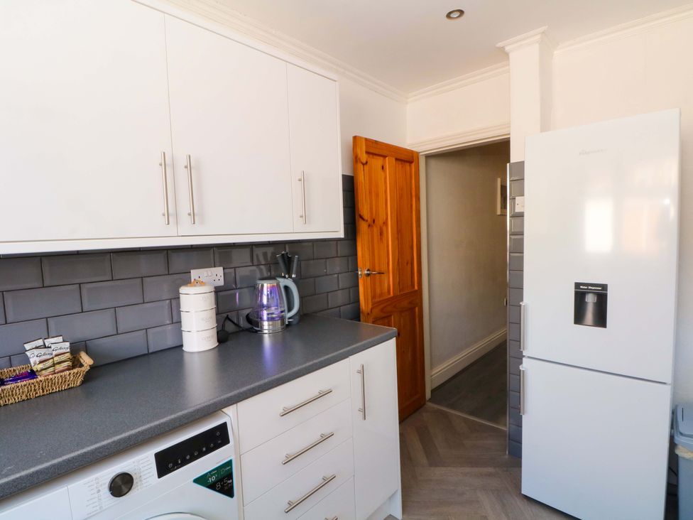 A kitchen with a washing machine, fridge, and kettle at Victoria Place in Accrington