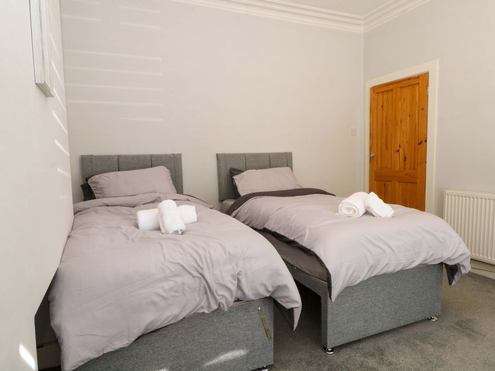 A bedroom with twin beds and a wooden door at Victoria Place in Accrington