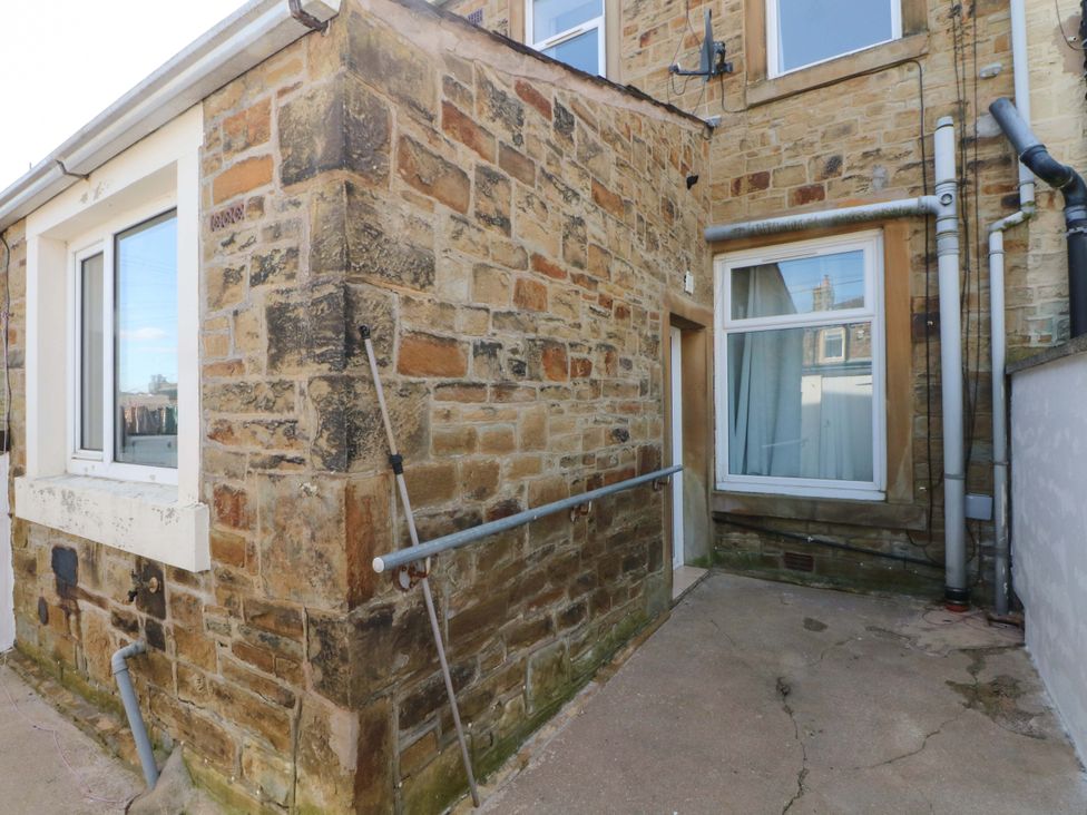 An outdoor area with a stone wall and a doorway at Victoria Place in Accrington